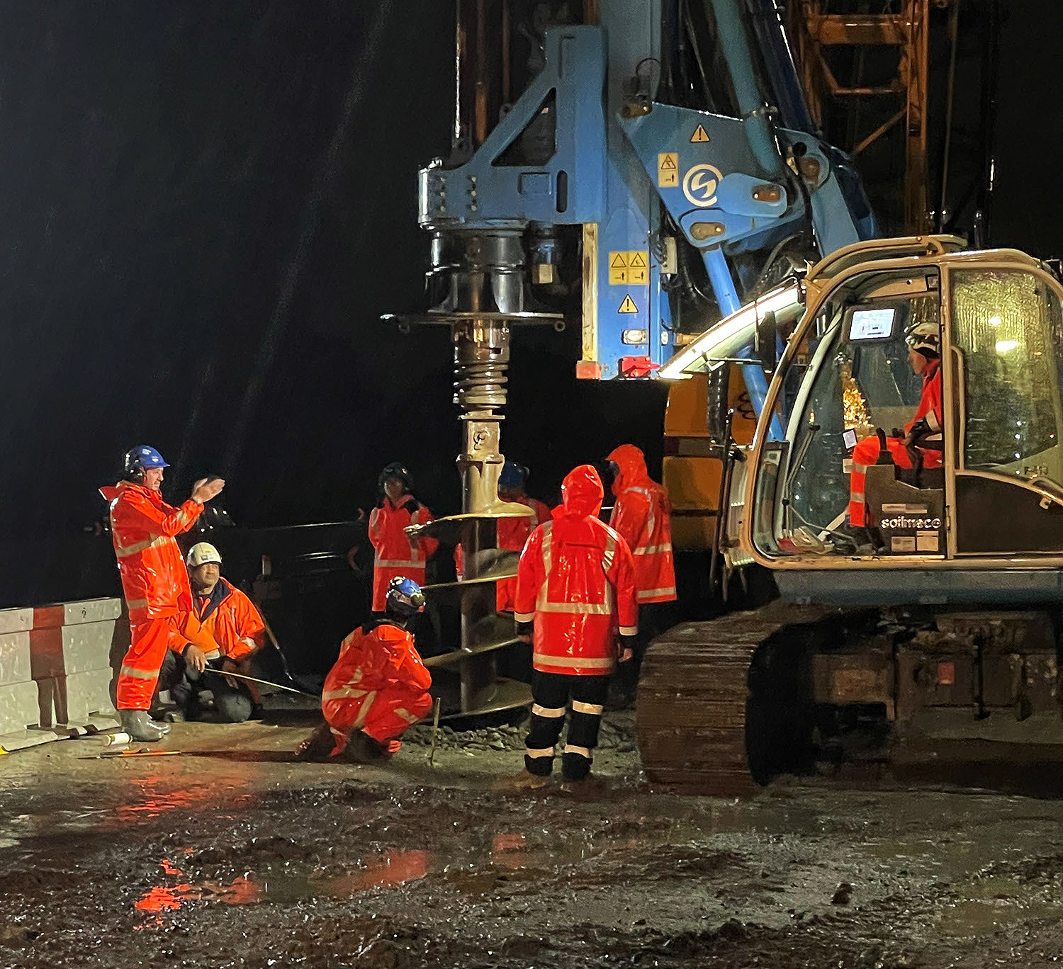 Spiral Drillers workers at night drilling a hole with an excavator